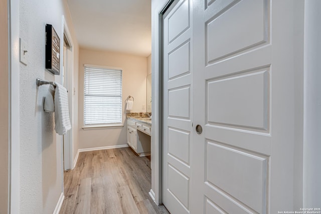 bathroom featuring baseboards, wood finished floors, and vanity
