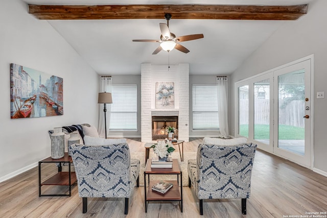living area featuring baseboards, a fireplace, a ceiling fan, and wood finished floors