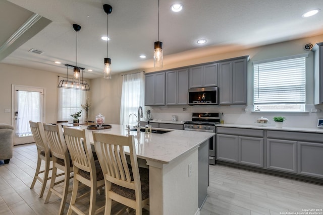13911 Lazada, San Antonio, TX 78245 - kitchen with a sink, appliances with stainless steel finishes, gray cabinets, a breakfast bar area, and an island with sink