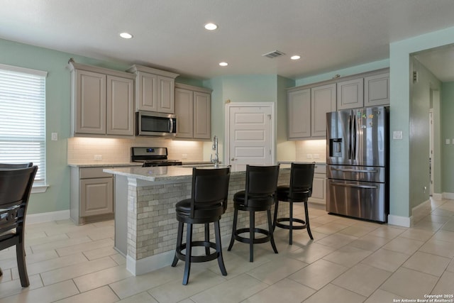 9407 Sundrop Vly, San Antonio, TX 78254 - kitchen featuring visible vents, a kitchen bar, gray cabinets, appliances with stainless steel finishes, and backsplash