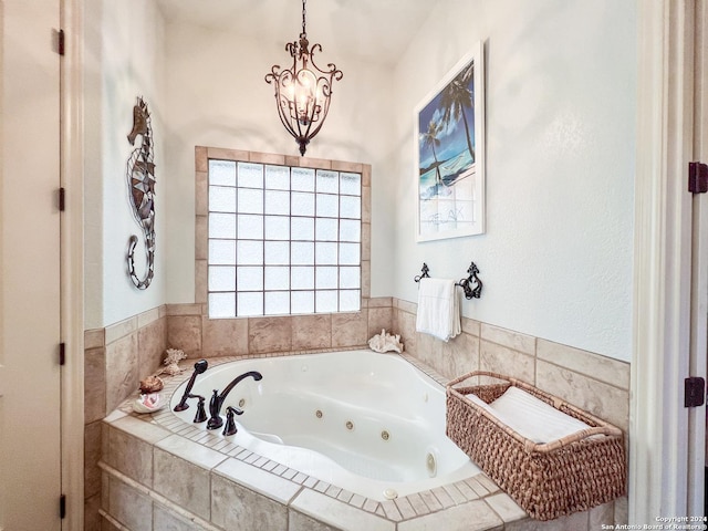 bathroom featuring a chandelier and a jetted tub
