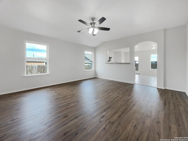 spare room with a ceiling fan, arched walkways, baseboards, lofted ceiling, and dark wood-type flooring