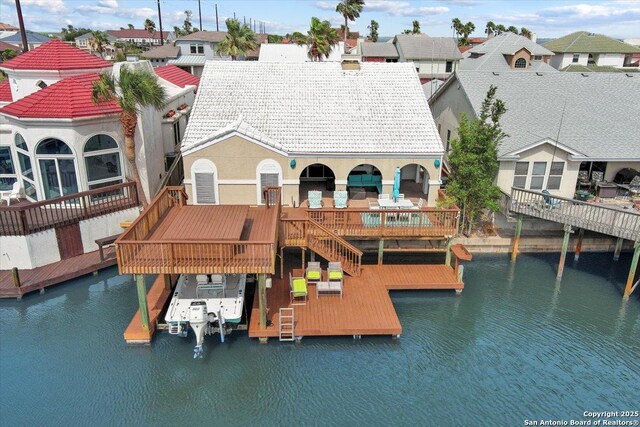 back of house featuring a tiled roof, a water view, a residential view, and boat lift