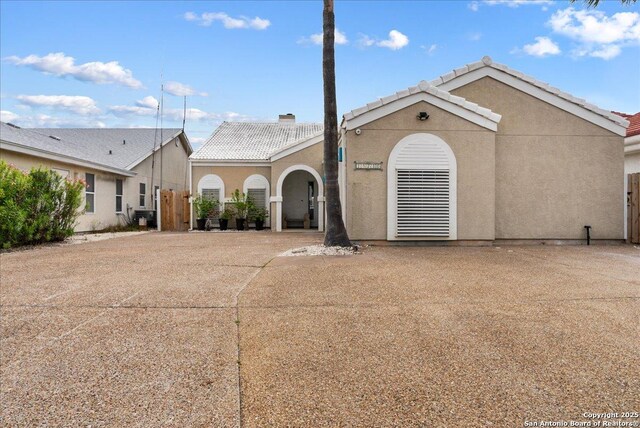 ranch-style home featuring fence, a tile roof, and stucco siding
