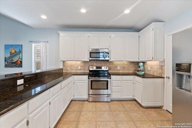 kitchen with white cabinetry, tasteful backsplash, dark stone countertops, appliances with stainless steel finishes, and light tile patterned floors