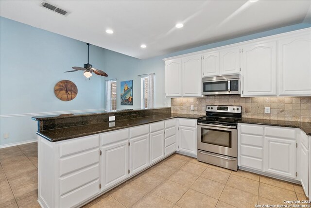 kitchen with appliances with stainless steel finishes, decorative backsplash, a peninsula, and visible vents