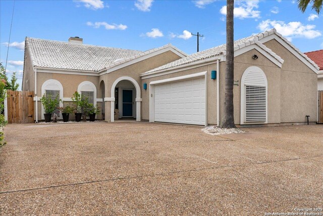 view of front of home featuring fence, a garage, a chimney, concrete driveway, and a tiled roof