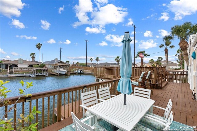 wooden deck featuring a water view, a residential view, and outdoor dining space