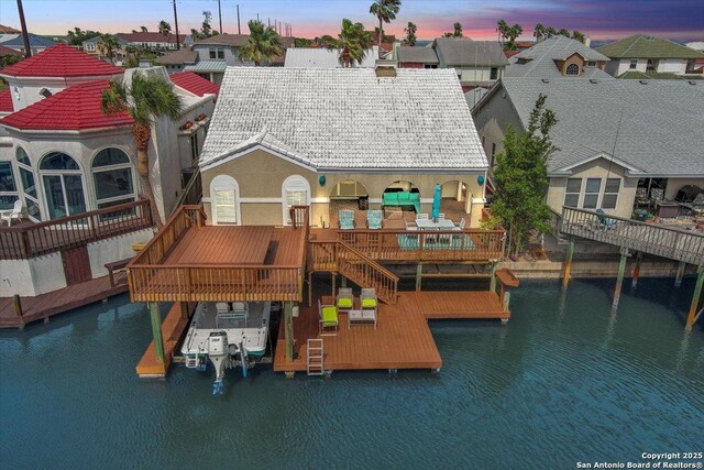 exterior space featuring a water view, stucco siding, boat lift, and a residential view