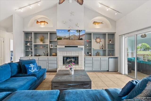 living area with light tile patterned flooring, high vaulted ceiling, track lighting, and a tile fireplace