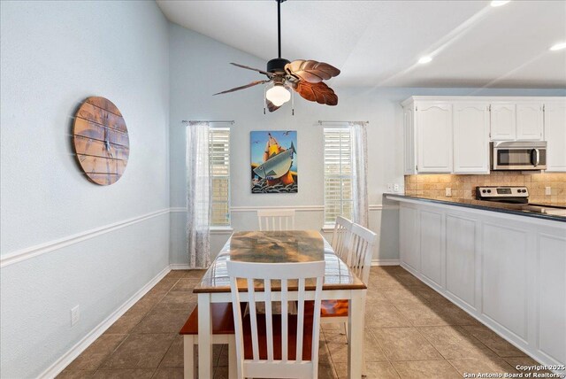 dining space featuring baseboards, ceiling fan, light tile patterned flooring, and vaulted ceiling