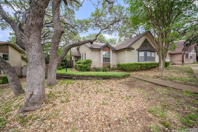 view of front of property with fence, roof with shingles, and brick siding
