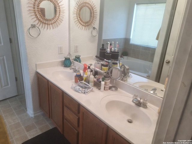 bathroom featuring a sink, a bath, a textured wall, and double vanity