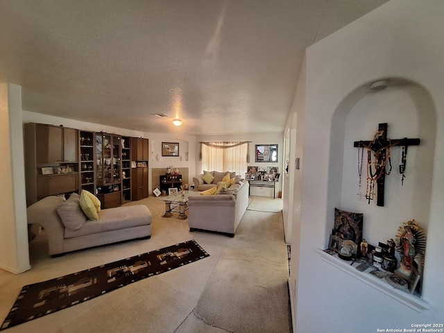 living room with light colored carpet, arched walkways, and a textured ceiling