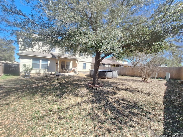 back of property with a hot tub, a patio, and a fenced backyard