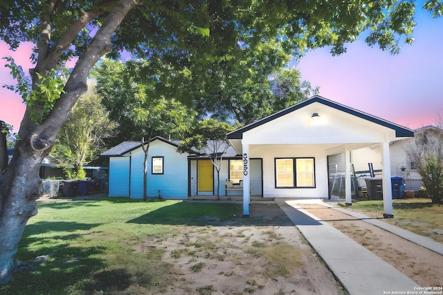 ranch-style house featuring a yard, fence, and covered porch