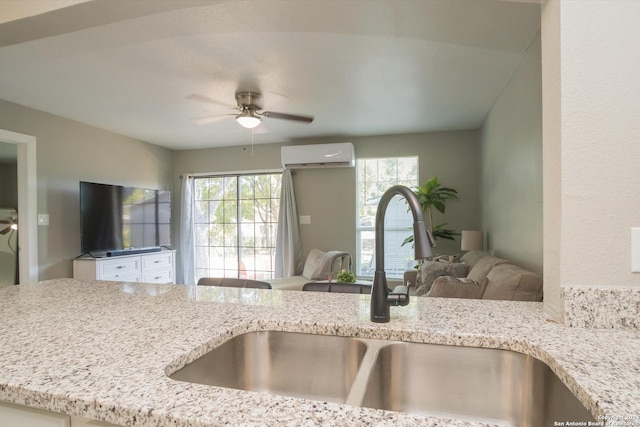 kitchen featuring a ceiling fan, open floor plan, plenty of natural light, a wall unit AC, and a sink