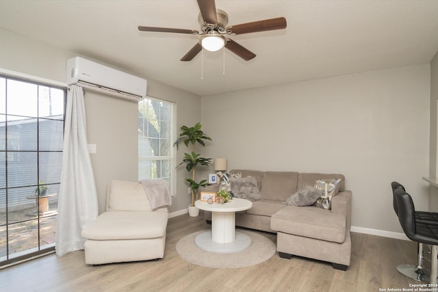living area with baseboards, a ceiling fan, a wall mounted air conditioner, and wood finished floors