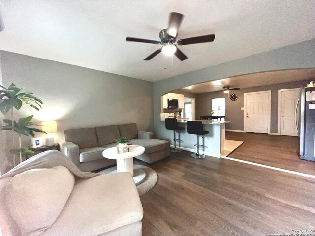living room featuring a ceiling fan, dark wood-style flooring, and arched walkways