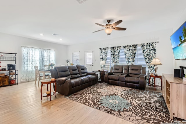 living room featuring light wood-type flooring, ceiling fan, and visible vents