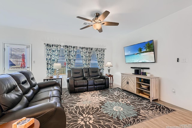 living room featuring baseboards, ceiling fan, and wood finished floors