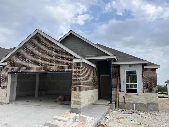 view of front of home featuring brick siding, a garage, driveway, and stone siding
