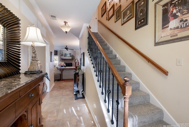 stairway with visible vents, a ceiling fan, baseboards, and ornamental molding