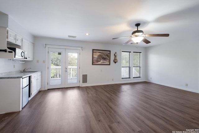 kitchen with a healthy amount of sunlight, white microwave, french doors, and white cabinetry