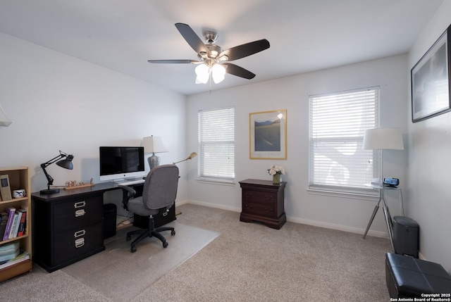 office space featuring baseboards, ceiling fan, light carpet, and a wealth of natural light