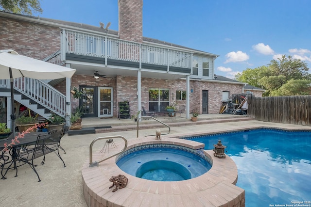 view of pool featuring fence, stairs, a pool with connected hot tub, ceiling fan, and a patio