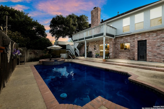 view of pool with a patio, a fenced backyard, a pool with connected hot tub, and stairs