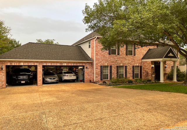view of front of house with roof with shingles, an attached garage, driveway, and brick siding
