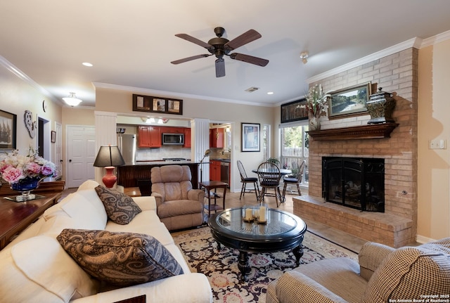 living room with crown molding, a ceiling fan, a brick fireplace, and visible vents