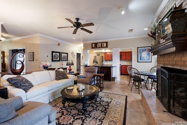 living room featuring crown molding, a ceiling fan, visible vents, and a fireplace