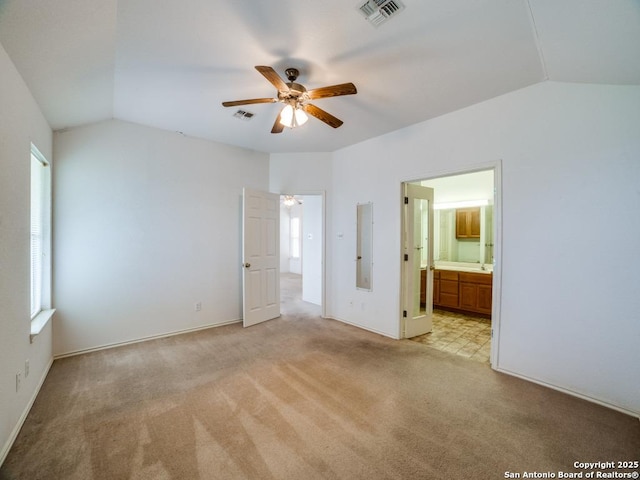 unfurnished bedroom with baseboards, light carpet, visible vents, and vaulted ceiling