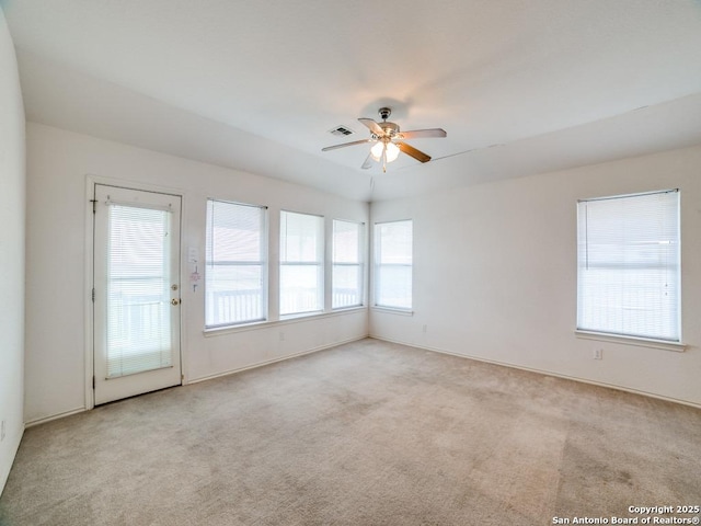 carpeted spare room with ceiling fan, baseboards, and visible vents