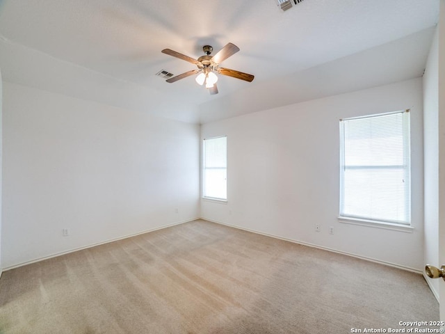 spare room featuring light carpet, baseboards, visible vents, and ceiling fan