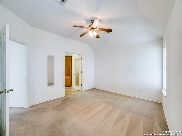 spare room featuring visible vents, baseboards, ceiling fan, light colored carpet, and vaulted ceiling