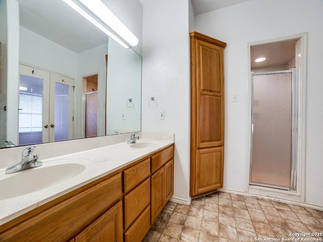full bathroom with a sink, double vanity, baseboards, and a shower stall