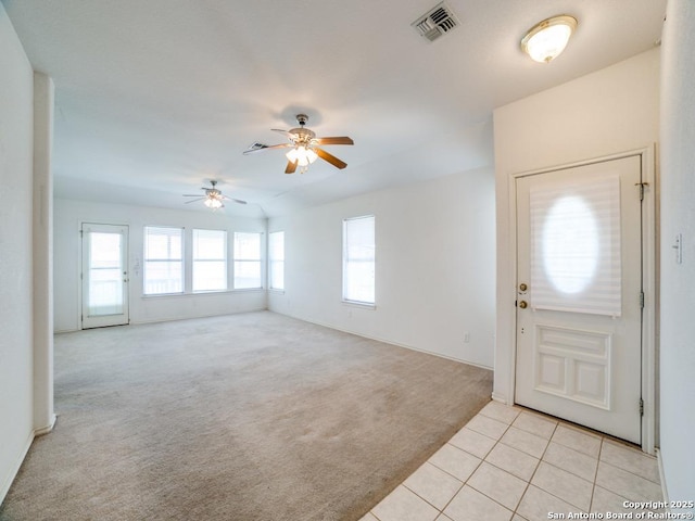 foyer with light tile patterned floors, ceiling fan, visible vents, and light colored carpet