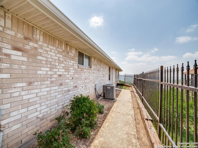 view of home's exterior with a fenced backyard, brick siding, and central AC