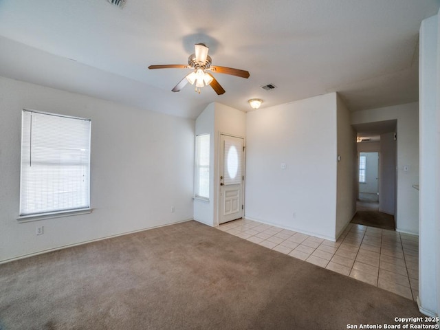 unfurnished room with light colored carpet, light tile patterned floors, visible vents, and a ceiling fan