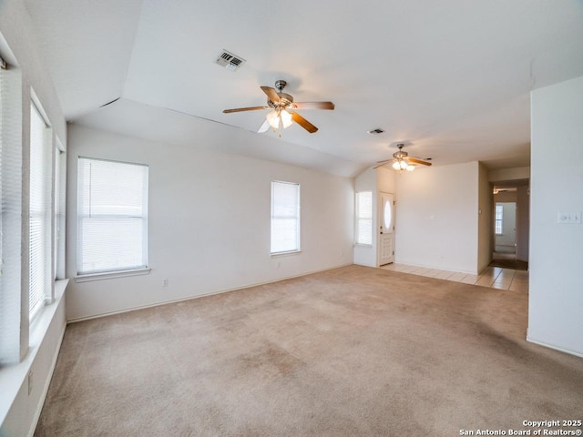 unfurnished room with light colored carpet, visible vents, lofted ceiling, and a ceiling fan