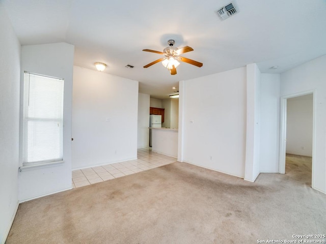 unfurnished living room with a ceiling fan, light carpet, light tile patterned floors, and visible vents