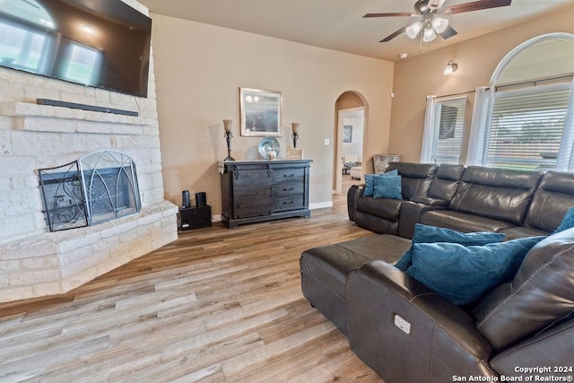15742 Chippewa Blvd, Selma, TX 78154 - living room with a stone fireplace, a ceiling fan, arched walkways, and wood finished floors