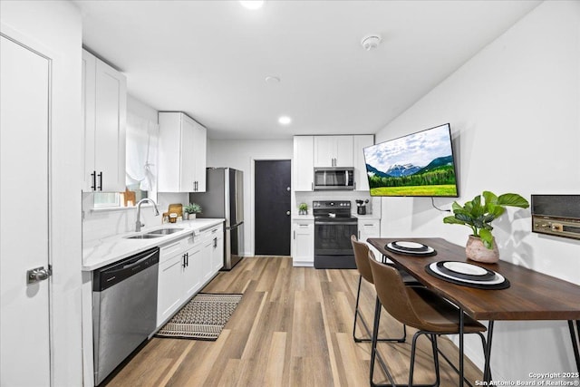 7722 Strolling Ln, Live Oak, TX 78233 - kitchen with white cabinets, stainless steel appliances, a sink, and light wood-style floors