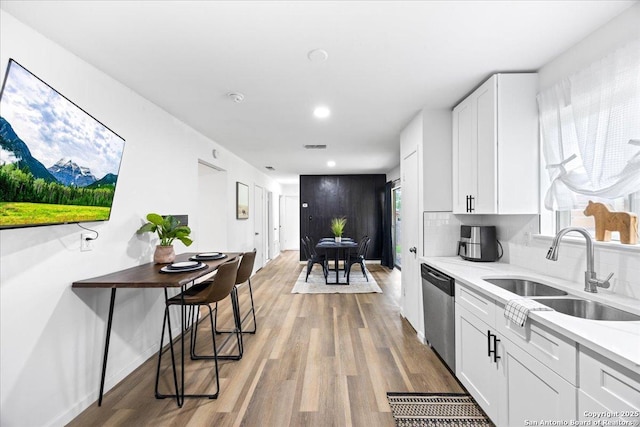 7722 Strolling Ln, Live Oak, TX 78233 - kitchen with dishwasher, white cabinets, a sink, light wood finished floors, and backsplash