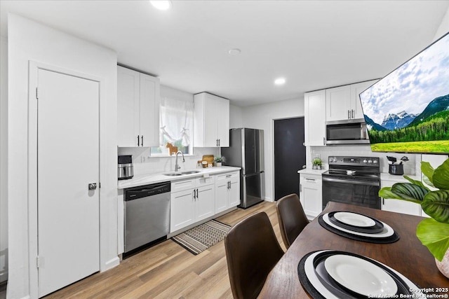 7722 Strolling Ln, Live Oak, TX 78233 - kitchen with a sink, appliances with stainless steel finishes, light wood-style flooring, and light countertops