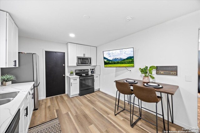 7722 Strolling Ln, Live Oak, TX 78233 - kitchen with baseboards, light wood-type flooring, white cabinets, light stone counters, and stainless steel appliances