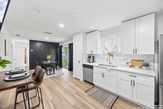 7722 Strolling Ln, Live Oak, TX 78233 - kitchen with stainless steel dishwasher, light wood-style floors, a sink, and tasteful backsplash